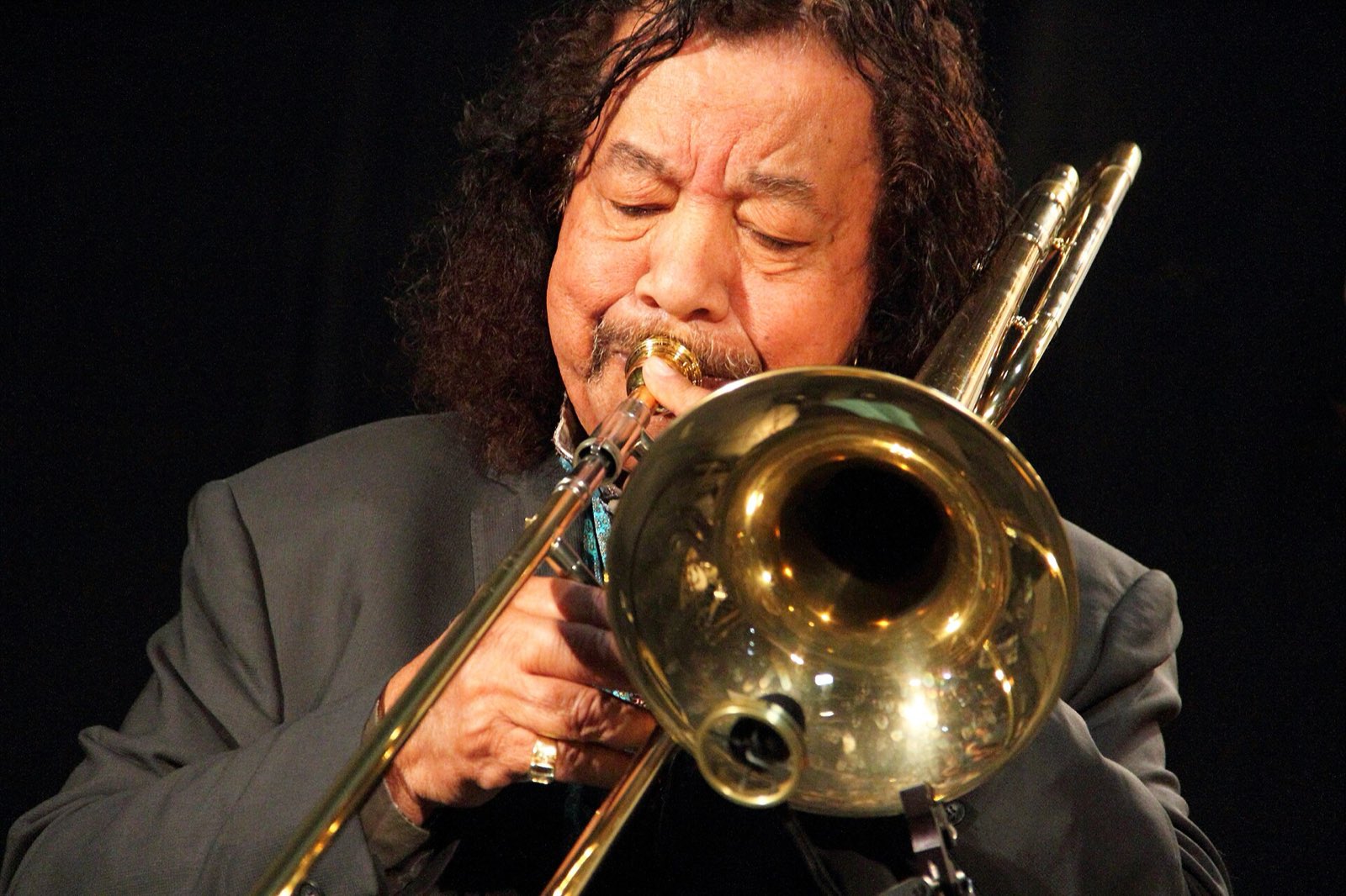 Raul de Souza tocando trombone em close, de olhos fechados, com a campana ocupando o centro da imagem.
